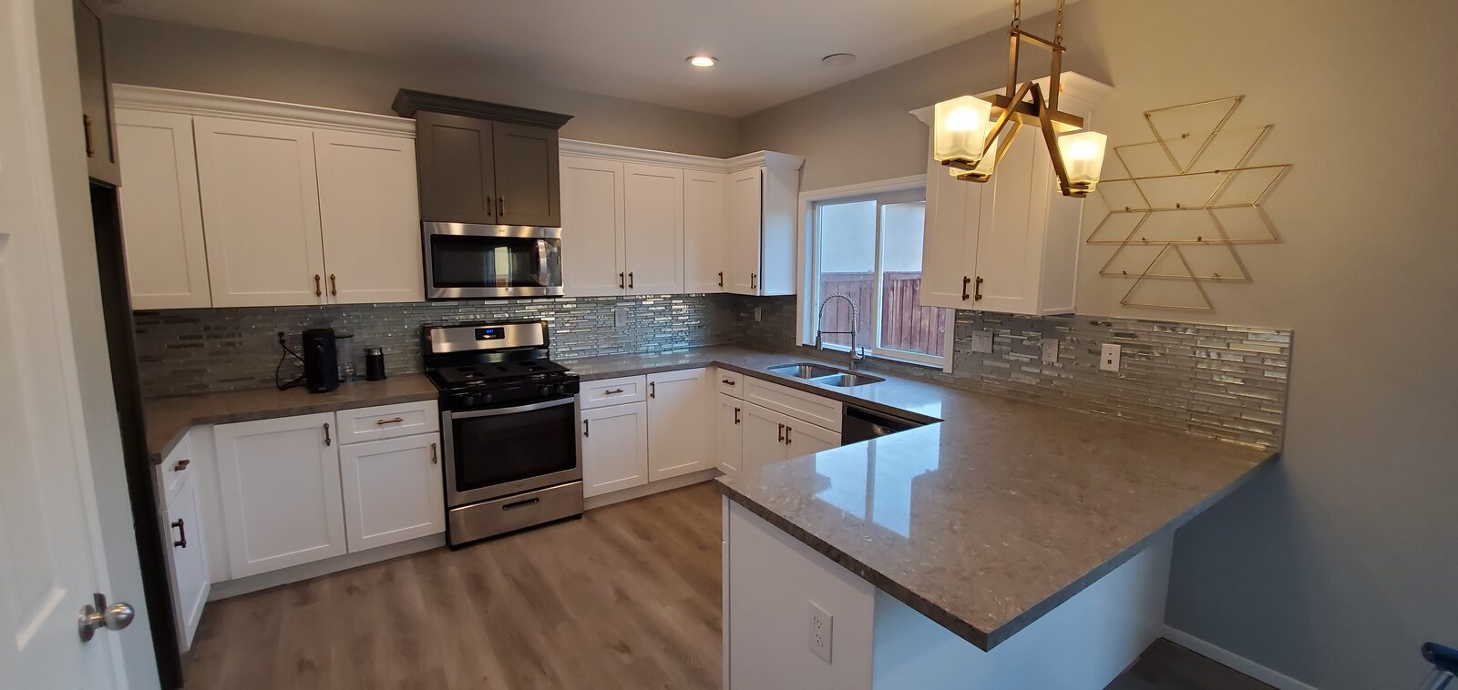 Kitchen remodel with white shaker cabinets, glass mosaic backsplash, quartz counters and a brass pendant fixture